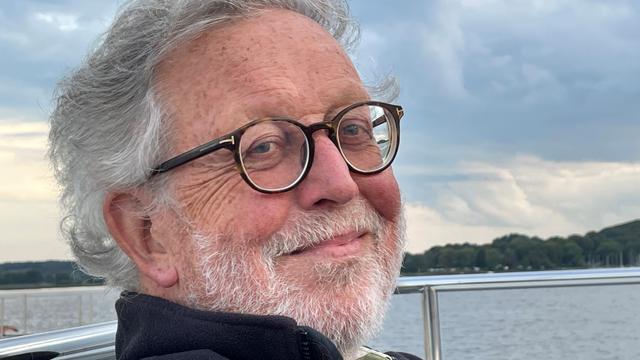 Der Schriftsteller Wolgang Hegewald sitzt auf einem Boot und lächelt in die Kamera.