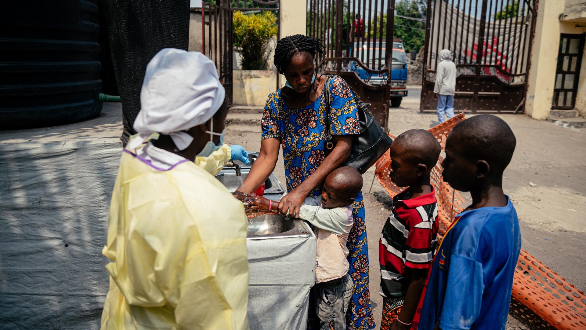 Eine Mutter hilft ihren Kindern, sich an einer Kontrollstelle die Hände zu waschen, bevor sie das Kyeshero-Krankenhaus in Goma betreten.