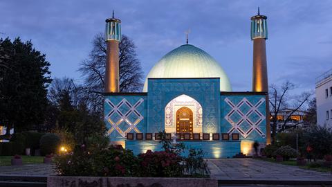 Blick auf das Islamische Zentrum Hamburg (IZH) der Imam-Ali-Moschee am frühen Abend. Das Gebäude hat ein hohes, großes Kuppeldach. Rechts und links stehen zwei Minarette. 
