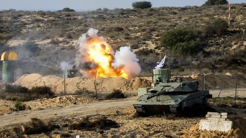 Eine Militärübung im Gazastreifen in der Wüste. Hinter einem Panzer ist eine Explosion zu sehen.