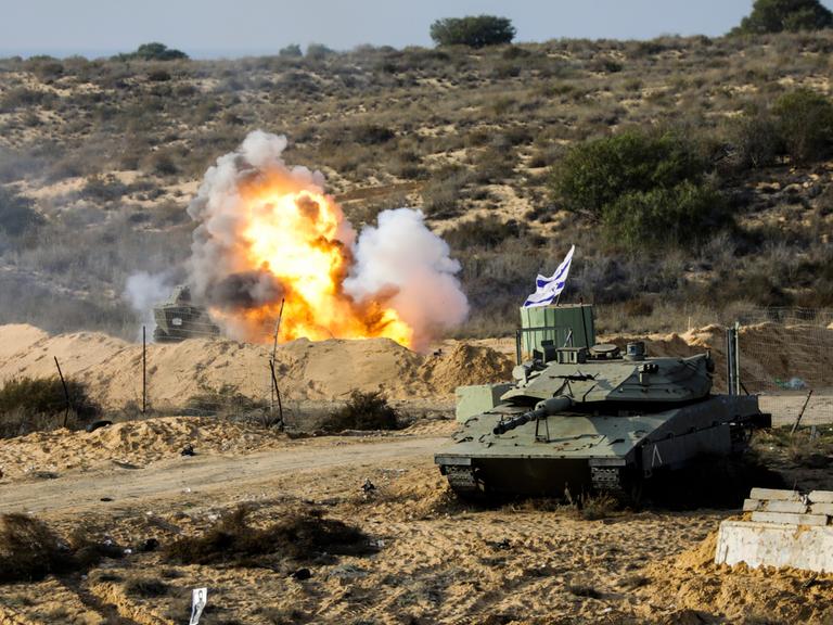 Eine Militärübung im Gazastreifen in der Wüste. Hinter einem Panzer ist eine Explosion zu sehen.