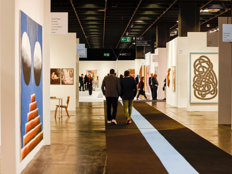 Besucher gehen bei der Eröffnung der Kunstmesse der Art Cologne durch die Hallen.