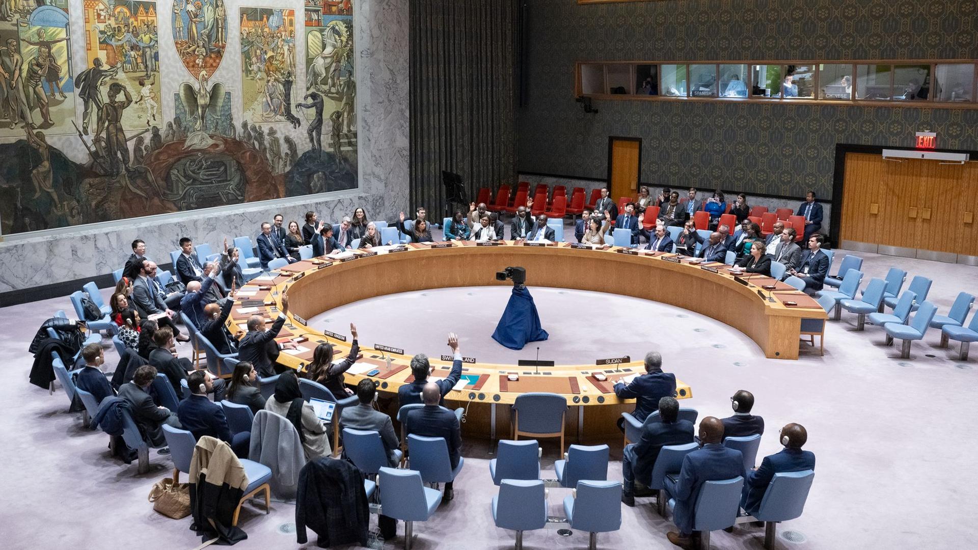 Die Delegierten im UNO-Sicherheitsrat heben die Hände zur Abstimmung, die Tische sind im Kreis angeordnet.