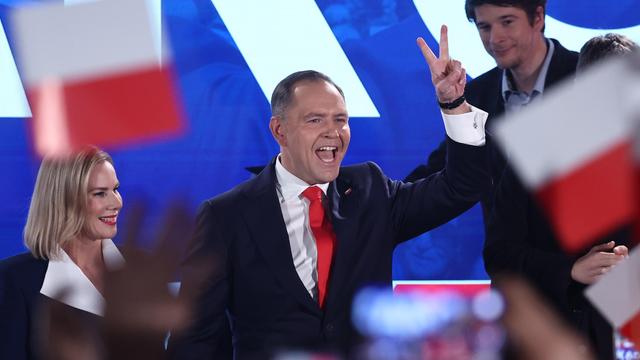 Der polnische Politiker Karol Nawrocki steht auf einer Bühne und zeigt das Siegeszeichen mit seinen Fingern.