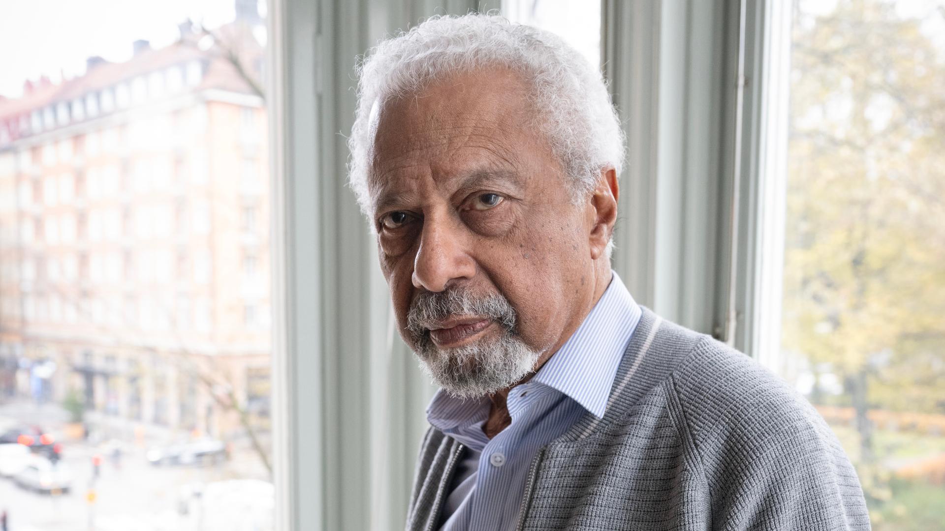 Der Schriftsteller Abdulrazak Gurnah im Porträt vor einem Fenster 