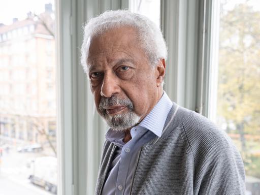 Der Schriftsteller Abdulrazak Gurnah im Porträt vor einem Fenster 