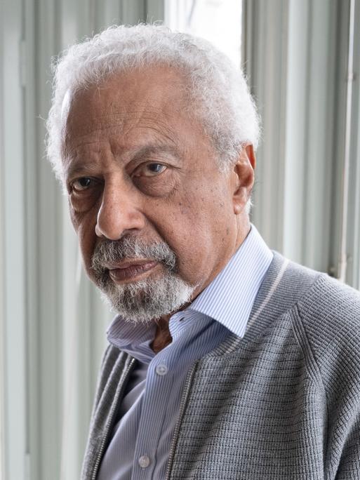 Der Schriftsteller Abdulrazak Gurnah im Porträt vor einem Fenster 