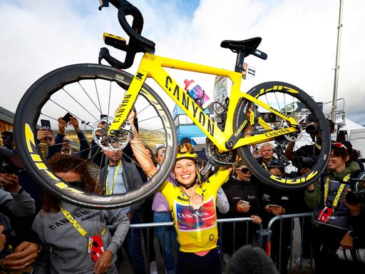 Die Gesamtsiegerin der Tour de France 2024 Femmes, Niewiadoma Katarzyna, jubelt im Gelben Trikot und hält ihr Rad in die Luft. 