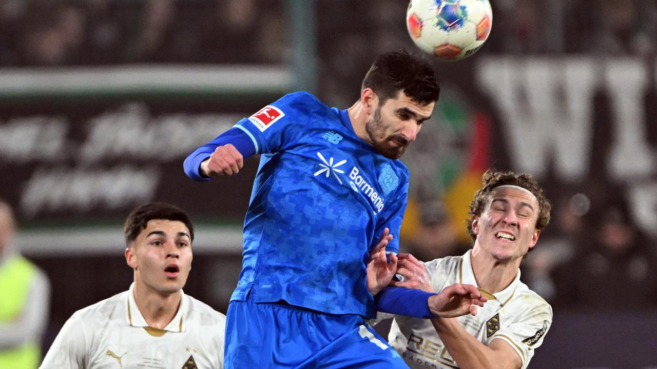 Terrier im blauen Trikot springt hoch und köpft den Ball. Swider steht mit geschlossenen Augen daneben. Etwas weiter hinten ein weiterer Gladbacher Spieler.