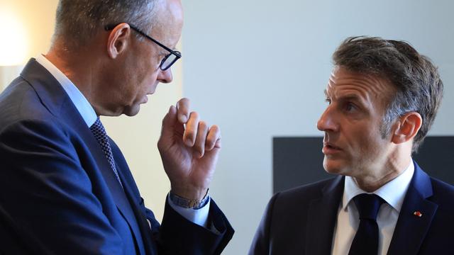 Bundeskanzler Merz und Frankreichs Präsident Macron stehen sich gegenüber und sprechen vertraulich miteinander.
