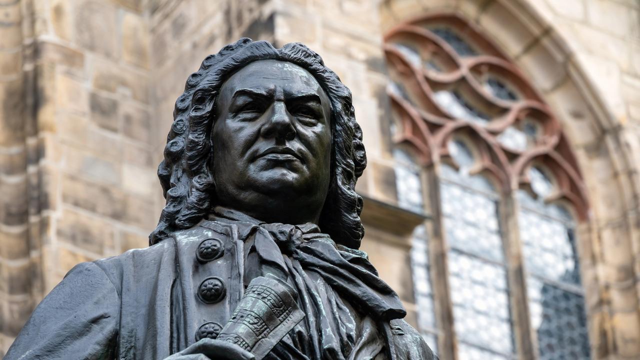 Blick auf den Kopf der Statue von Johann Sebastian Bach vor der Thomaskirche Leipzig, die ihn mit Perücke und Notenrolle in der Hand zeigt