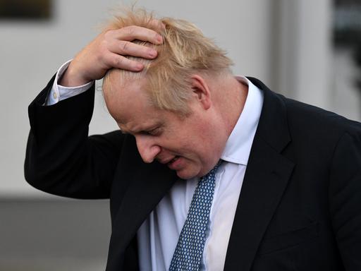 Großbritanniens Premierminister Boris Johnson streicht sich erschöpft durch sein Haar.