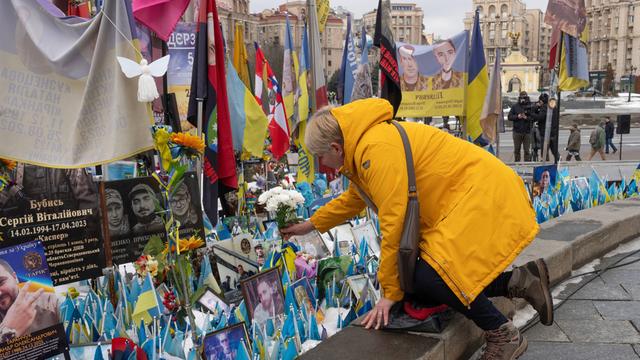 Eine Frau legt Blumen am Denkmal für die gefallenen ukrainischen Soldaten auf dem Unabhängigkeitsplatz in Kiew ab.