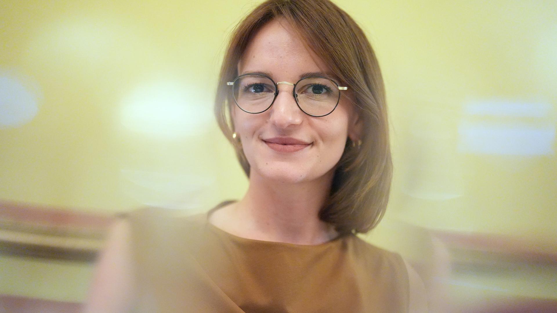 Jehona Kicaj lächelt in die Kamera. Sie trägt eine Brille und einen mittelbraunen Bob. Jehona Kicaj lächelt in die Kamera. Sie trägt eine Brille und einen mittelbraunen Bob.