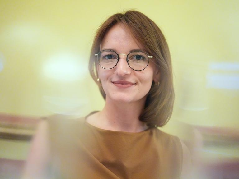 Jehona Kicaj lächelt in die Kamera. Sie trägt eine Brille und einen mittelbraunen Bob.