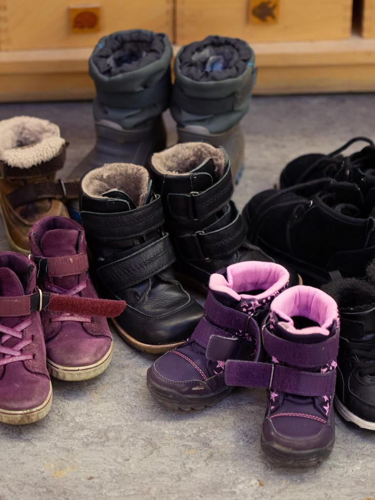 Kinderschuhe und Kinderstiefel sind auf dem Boden in einer Kindertagesstätte abgestellt. 
