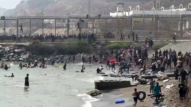 Menschen steigen, teils mit Schwimmreifen, am Strand der spanischen Exklave Ceuta aus dem Wasser.