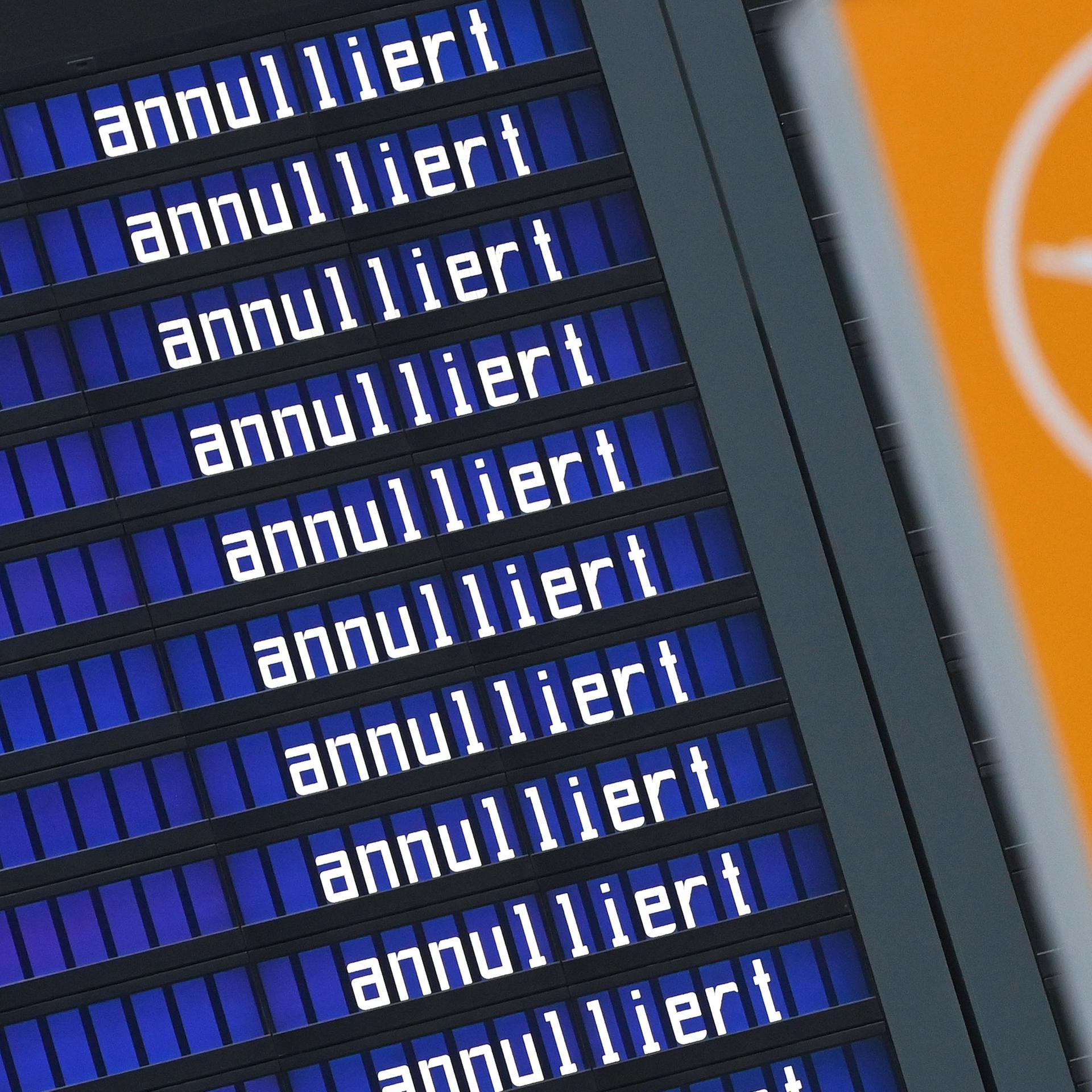Eine Anzeigetafel mit der sich wiederholenden Aufschrift "annulliert". Daneben das Logo der Lufthansa mit einem Kranich. 