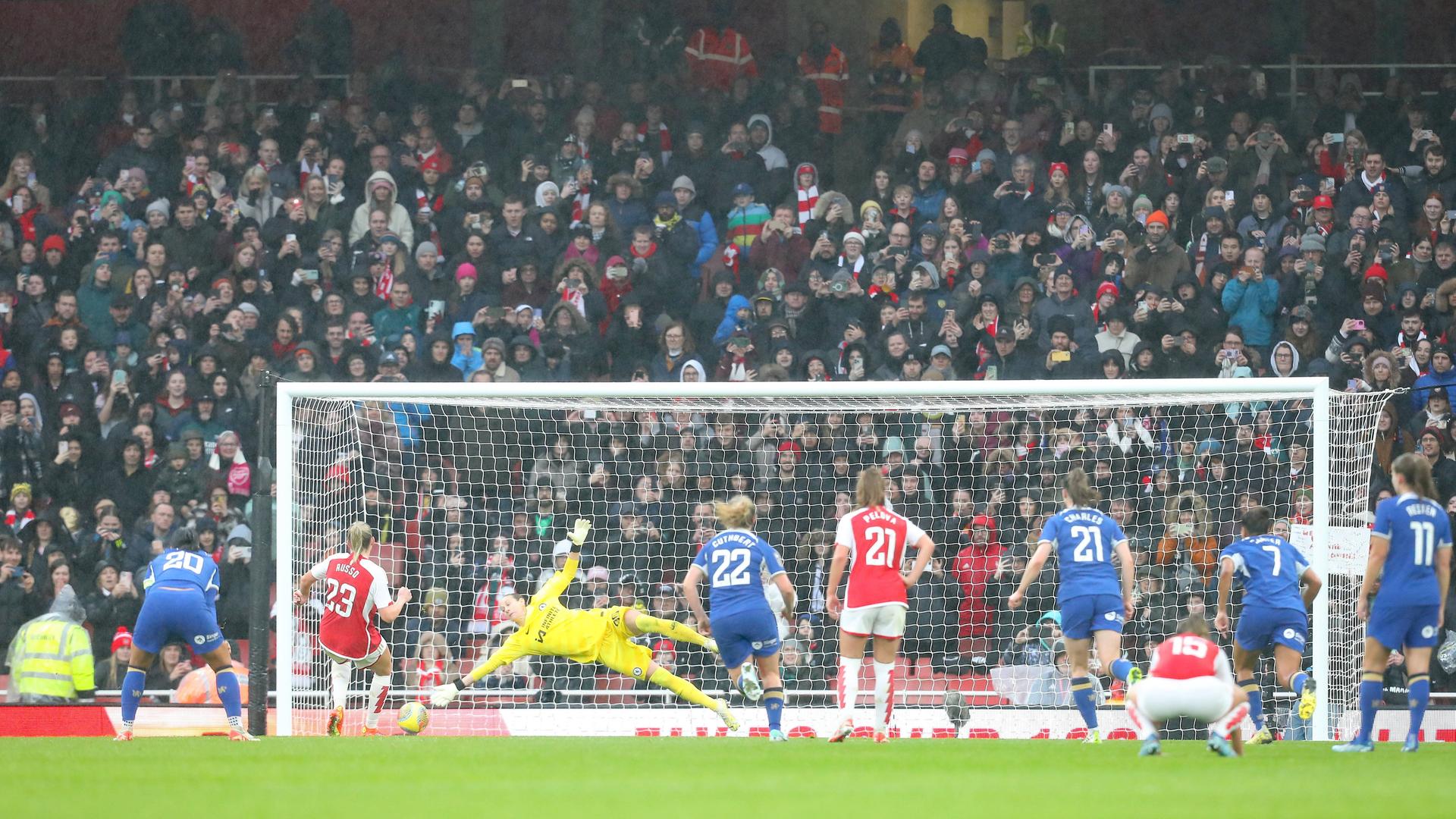 Spielszene: Die Torhüterin von Chelsea streckt sich nach einem Ball, der auf's Tor geht. Im Hintergrund eine vollbesetzte Tribüne.