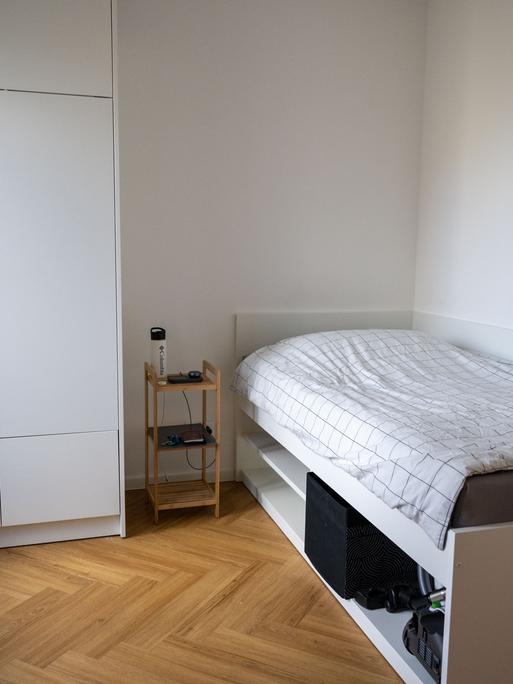 Die Werkswohnung der Charité in Berlin ist mit einem Bett, einem Nachttisch, einem Kleiderschrank und einem Stuhl möbliert.