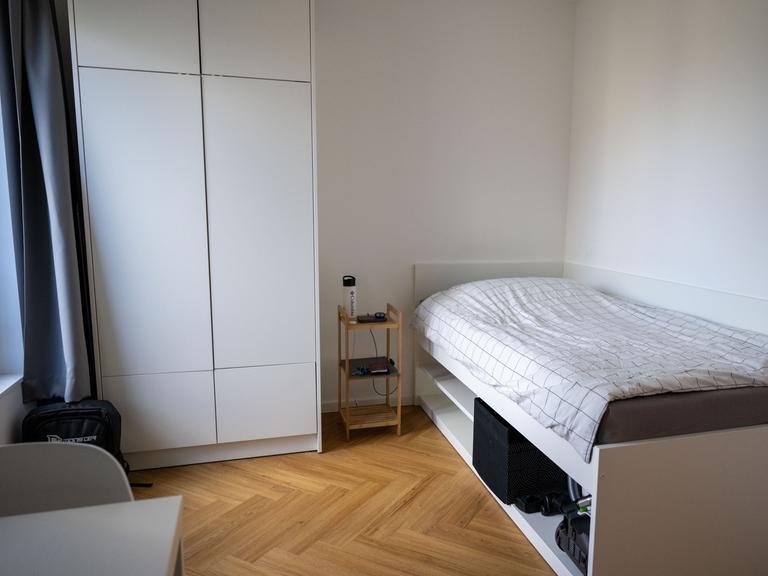 Die Werkswohnung der Charité in Berlin ist mit einem Bett, einem Nachttisch, einem Kleiderschrank und einem Stuhl möbliert.