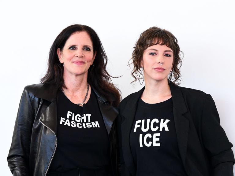 Die Filmemacherinnen Laura Poitras (links) und Rachel Lauren Mueller (rechts) ganz in schwarz gekleidet. Auf dem T-Shirt von Poitras steht "Fight Faschism" (Bekämpfe Faschismus), auf dem T-Shirt von Mueller "Fuck ICE". 