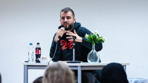 Der Pädagoge Burak Yilmaz bei einer Lesung mit Mikrofon.