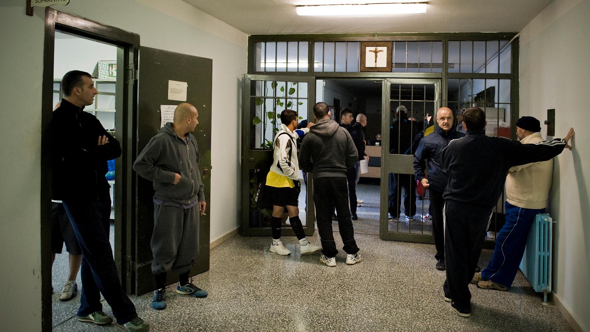 Junge und ältere Inhaftierte stehen in einem Gang des Bollate Gefängnisses.