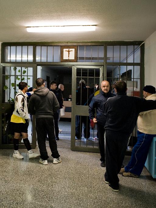 Junge und ältere Inhaftierte stehen in einem Gang des Bollate Gefängnisses.