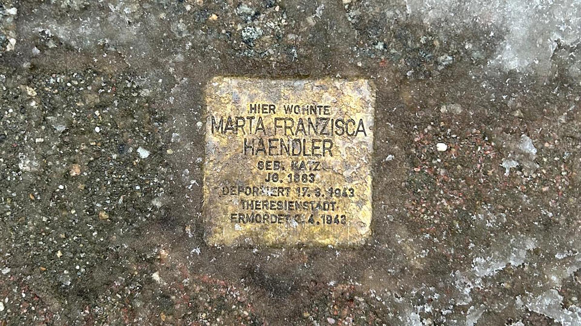 Hände mit Kelle und Zement setzen einen Stolperstein in den Boden. Die Steine erinnern an Personen, die von den Nazis deportiert und umgebracht wurden (Symbolbild).