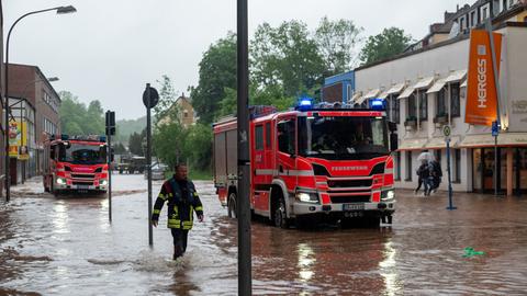 Feuerwehrleute bewegen sich und ihre LKW durch das Hochwasser in der Fischbachstrasse in Saarbrücken. Nach starken Regenfällen steht diese teilweise unter Wasser.