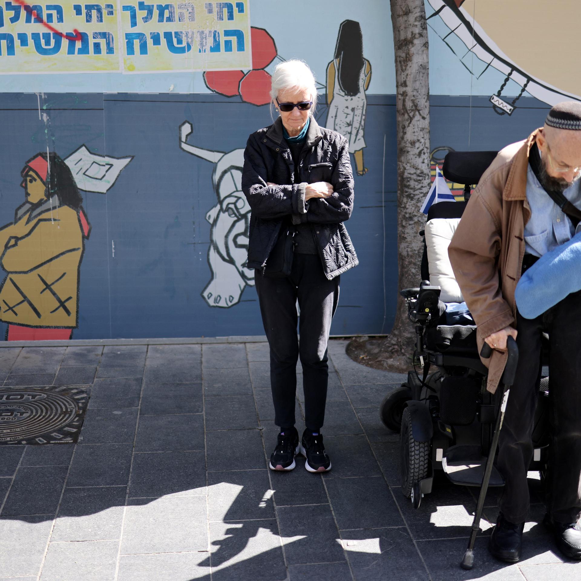 Menschen stehen in Schweigen auf der Straße während Sirenen heulen.