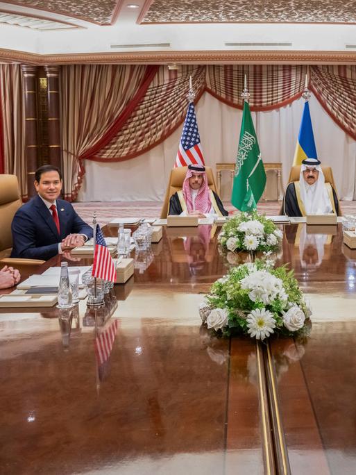 Im Dschidda sitzen Mike Waltz und  Marco Rubio (USA), der saudi-arabische Außenminister Prinz Faisal bin Farhan und Sicherheitsberater Mosaad bin Mohammad al-Aiban sowie der ukrainische Außenminister Andrii Sybiha und Andriy Yermak an einem Tisch.