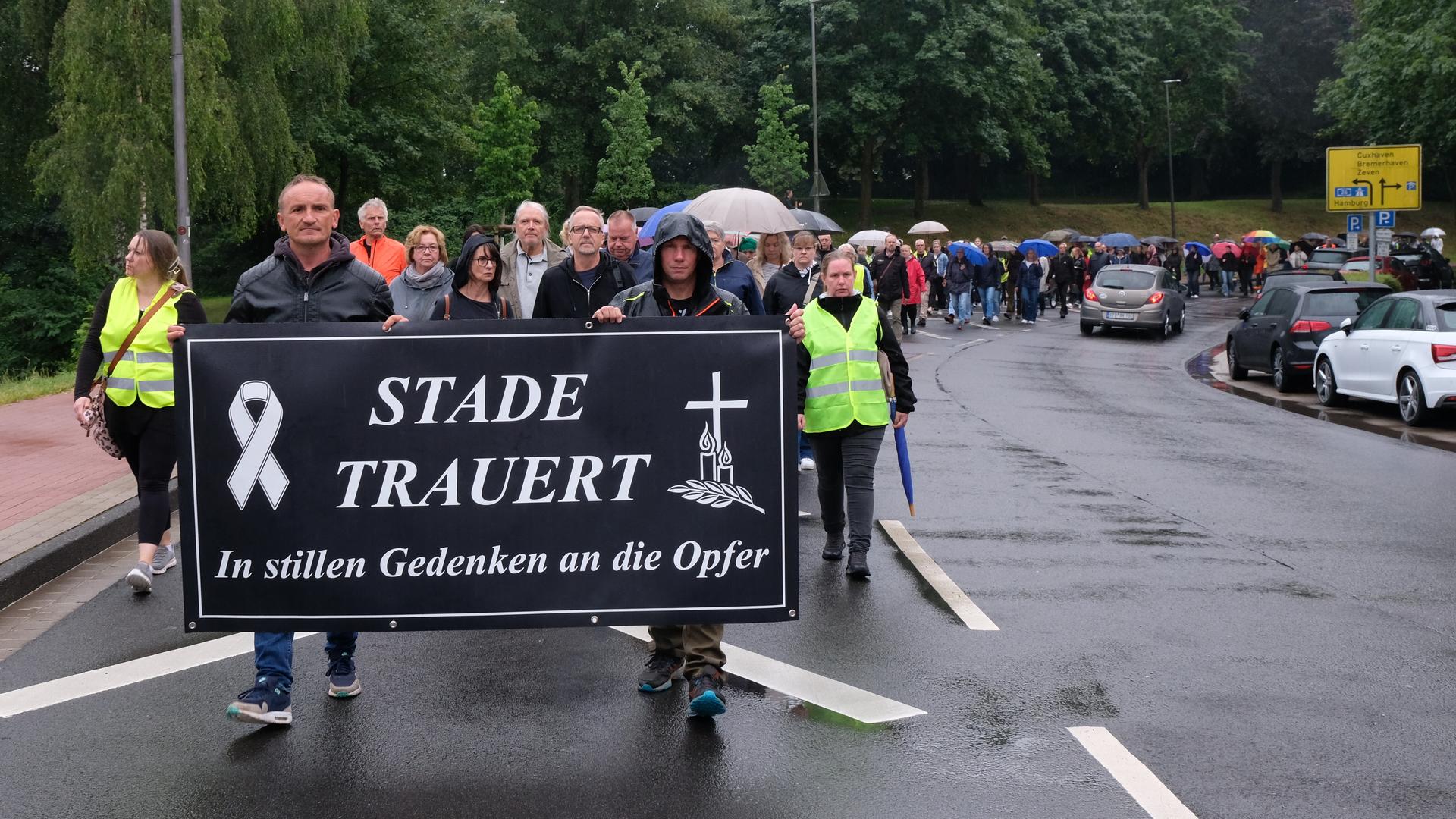 Viele Menschen laufen hinter einem schwarzen Banner. Es trägt in weißen Buchstaben die Aufschrift: "Stade trauert. In stillem Gedenken an die Opfer."