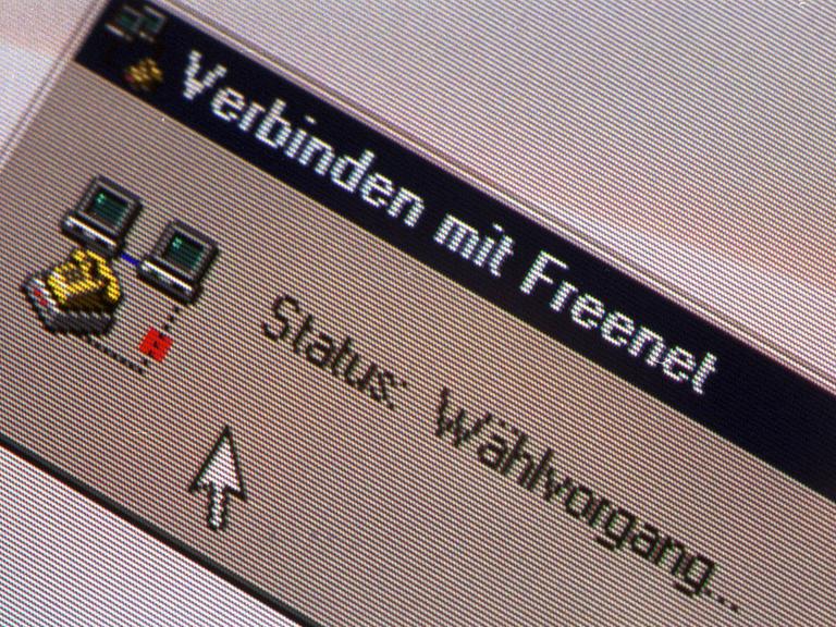 Die Älteren erinnern sich: Das Einwahlsymbol des Modems ploppte auf, wenn man sich mit dem Internet verband. Zu sehen sind zwei Bildschirme, zwischen denen ein gestricheltes Kabel-Symbol und ein Telefon stehen. 