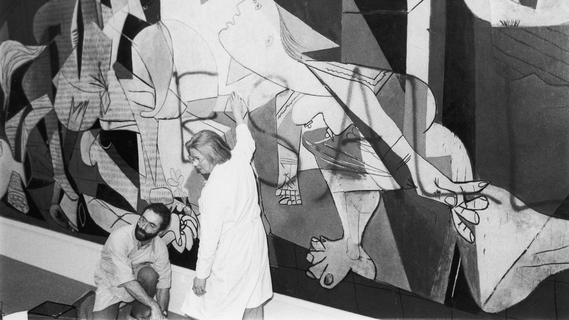 Ein Mann und eine Frau entfernen Farbe von Pablo Picassos Bild "Guernica" im Jahr 1974.
