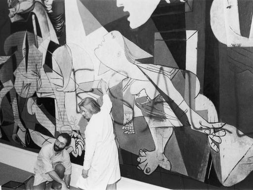 Ein Mann und eine Frau entfernen Farbe von Pablo Picassos Bild "Guernica" im Jahr 1974.