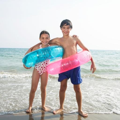 Junge und Mädchen (8–10) am Strand, mit Schwimmringen, Porträt
