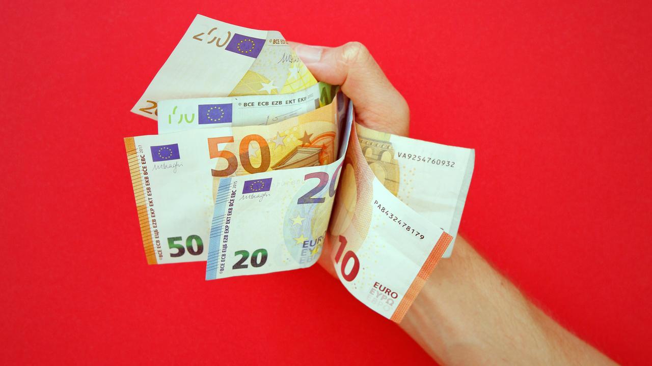 Ein Mann hält einige Euro-Geldscheine in seiner Hand.