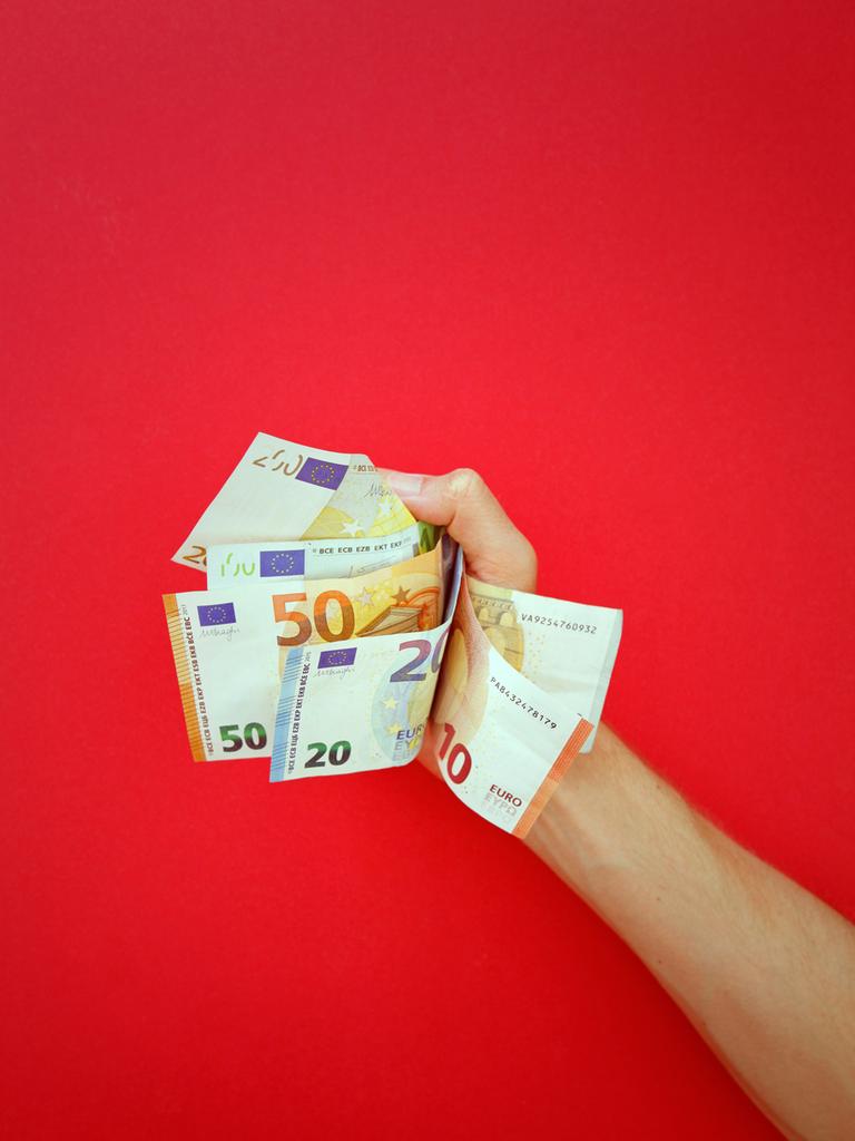 Ein Mann hält einige Euro-Geldscheine in seiner Hand. Ein Mann hält einige Euro-Geldscheine in seiner Hand.