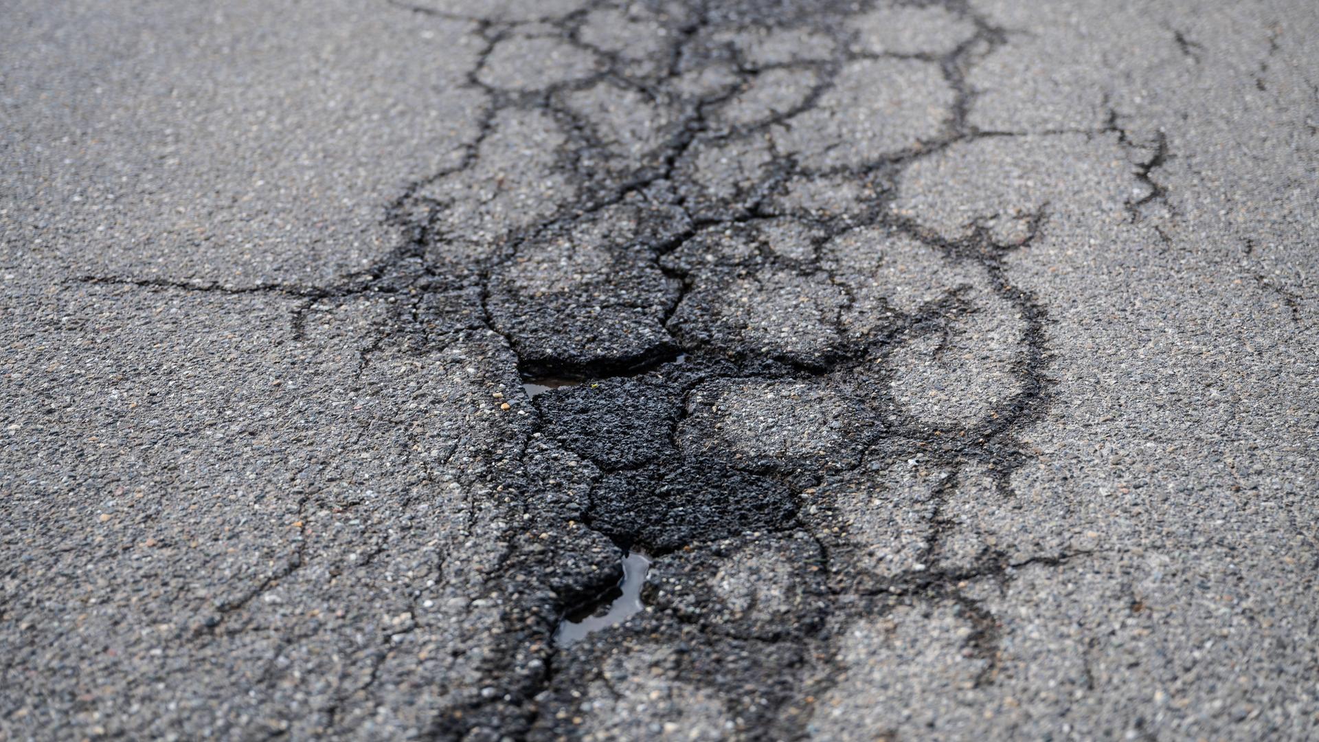 Risse und Schlaglöcher auf einer asphaltierten Straße. Risse und Schlaglöcher auf einer asphaltierten Straße.