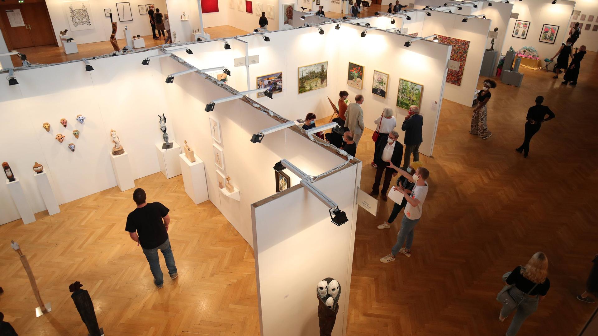 Blick von oben auf die Messe für zeigenössische Kunst in Magdeburg. Menschen stehen vor Trennwänden und betrachten Kunstwerke. Blick von oben auf die Messe für zeigenössische Kunst in Magdeburg. Menschen stehen vor Trennwänden und betrachten Kunstwerke.