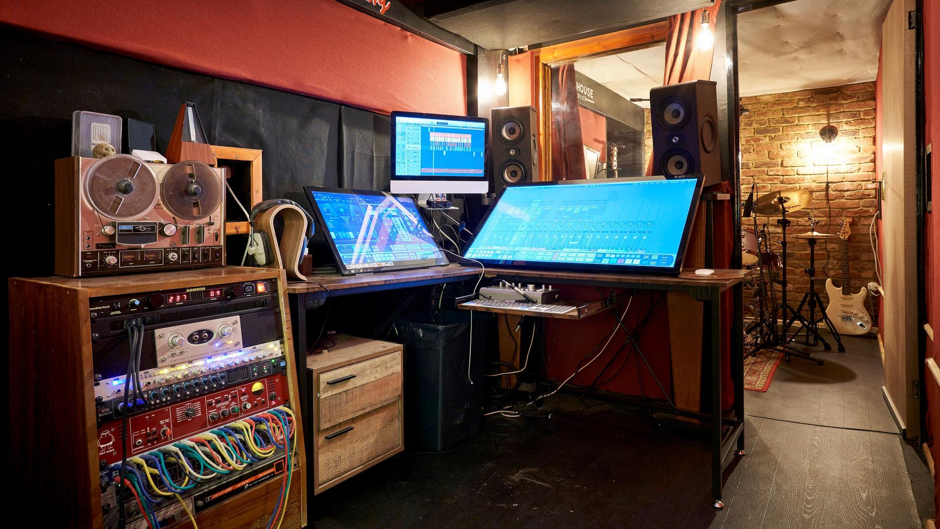 Einrichtung eines Tonstudios mit Bildschirmen, Lautsprechern und Patchfeldern mit Kabelverbindungen.