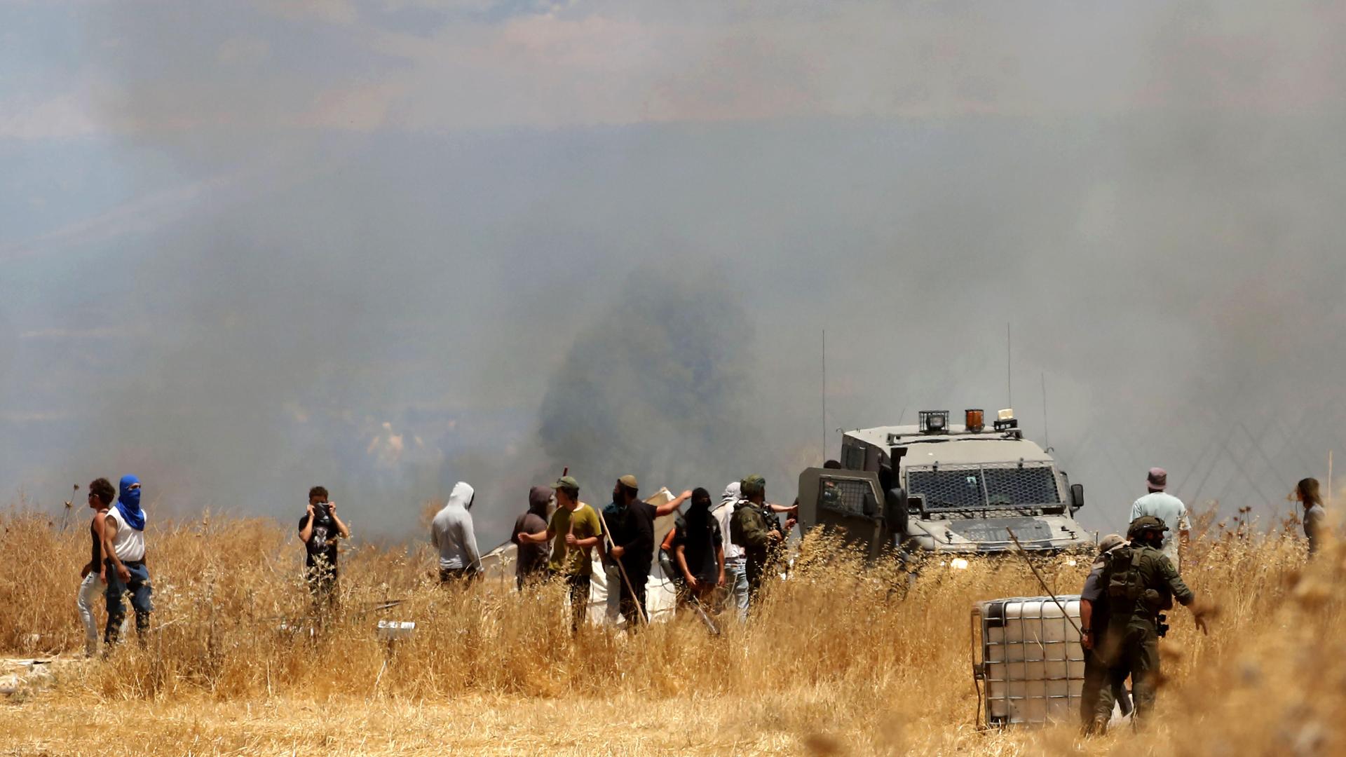 In der Nähe von Nablus gab es erneut Gewalt zwischen israeIischen Siedlern und Palästinensern. Menschen stehen auf einem Feld, dahinter steigt Rauch auf. In der Nähe von Nablus gab es erneut Gewalt zwischen israeIischen Siedlern und Palästinensern. Menschen stehen auf einem Feld, dahinter steigt Rauch auf.
