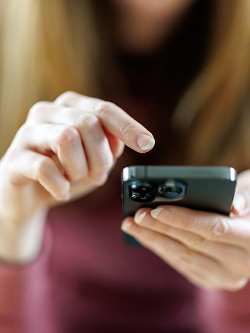 Eine junge Frau benutzt ein Smartphone.