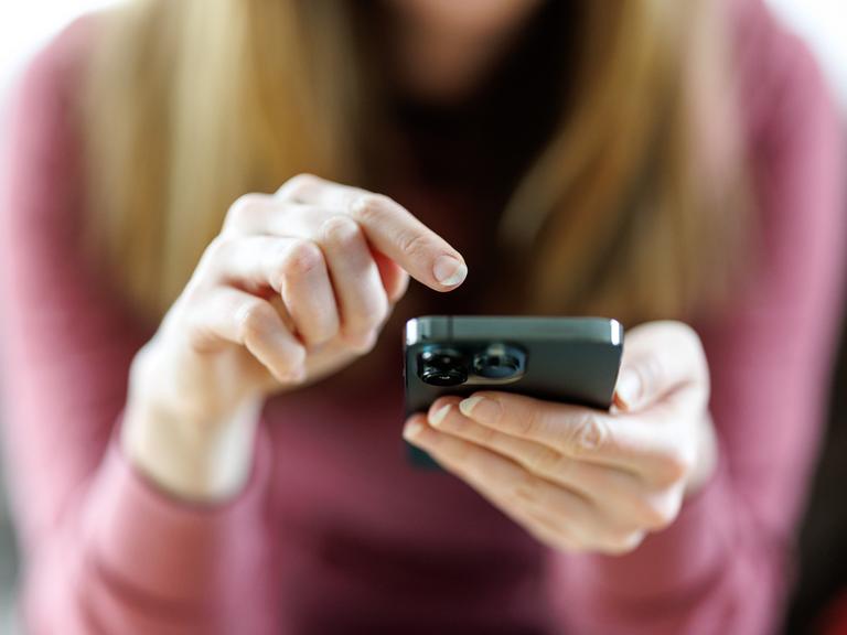 Eine junge Frau benutzt ein Smartphone.