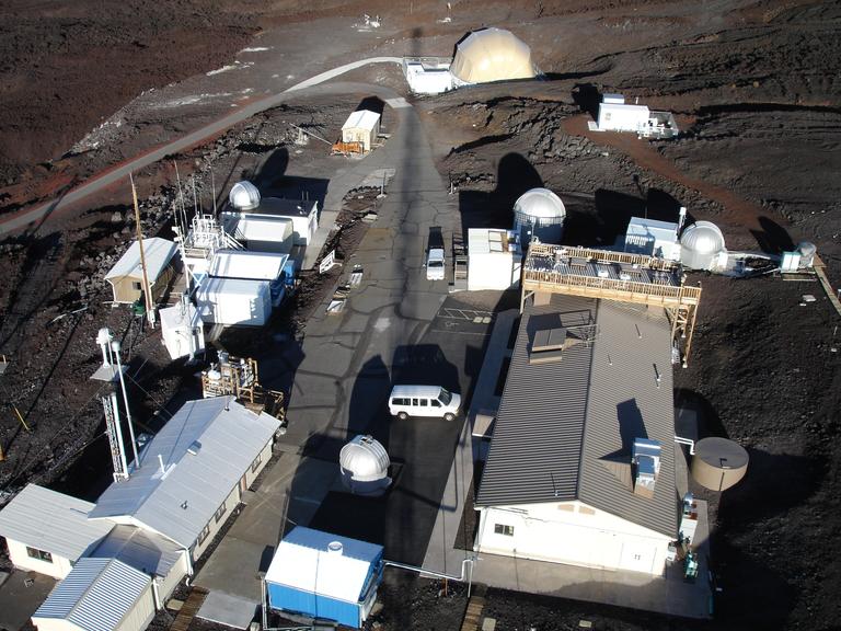 Die Station Mauna Loa auf Hawaii. Seit 1958 messen Wissenschaftler die CO2-Konzentration in der Luft, es ist die älteste Kohlendioxid-Messstation der Welt. Die karge Landschaft und die Gebäude wirken, als handele es sich um eine Marsstation.