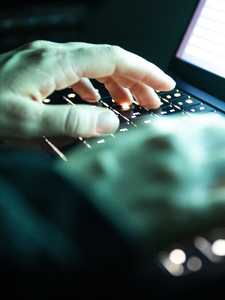 Eine Person tippt mit den Fingern auf einer beleuchteten Laptop-Tastatur.