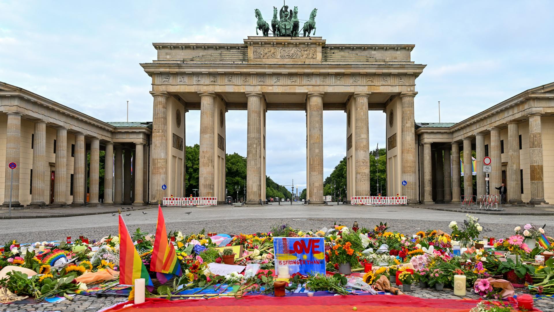Blumen, Kerzen, Botschaften und eine Regenbogenfahne sind am Morgen auf dem Pariser Platz vor dem Brandenburger Tor zu sehen. Im Tiergarten war am Rande des Christopher Street Day ein Mann mit einem Fahrzeug in eine Menschenmenge gefahren.