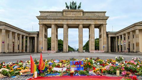 Blumen, Kerzen, Botschaften und eine Regenbogenfahne sind am Morgen auf dem Pariser Platz vor dem Brandenburger Tor zu sehen. Im Tiergarten war am Rande des Christopher Street Day ein Mann mit einem Fahrzeug in eine Menschenmenge gefahren.